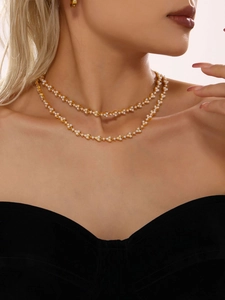 Close-up of double-layer pearl necklace and gold link chain on a female model