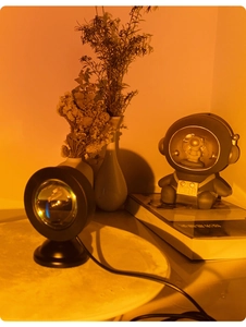 Detail of warm orange sunset lamp projection next to an astronaut figurine