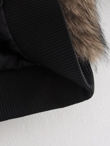 Dettaglio delle cuciture a contrasto tra polsini in maglia nera e materiale della pelliccia