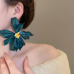 Detail of a large dark green acrylic flower earring with yellow stamen on a model