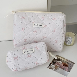 Macro detail of quilted white fabric with pink bows and grey polka dots makeup bags