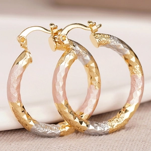 Macro shot of tricolor hammered texture earrings with gold, rose gold and silver finish