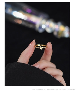Close-up of golden butterfly ring with twisted band and sparkling zircon details