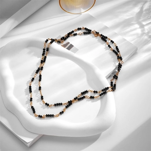 Minimalist double-layer gold chain necklace with black crystal beads on white tray