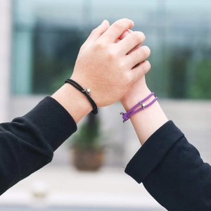 Gros plan de bracelets de couple magnétiques en corde milanaise tressée noire et violette