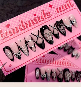 Detail of press-on nails with silver bows, pearls, and black velvet ribbons on pink almond base