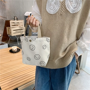 Corduroy tote bag with black smile pattern shown in a lifestyle cafe setting