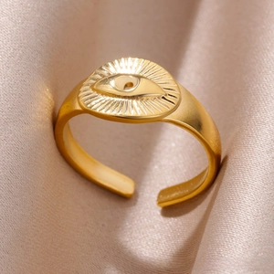Detail of gold evil eye open ring with sunburst texture on champagne satin background