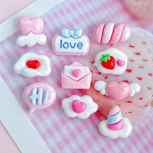Close-up of pink and white resin charms featuring heart and cloud shapes for DIY crafts