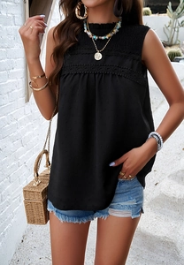Detail of a black sleeveless summer top featuring polka dot texture and lace trim details