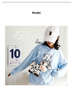 Detail of cute cow plush crossbody bag with 3D horns on casual sweatshirt model