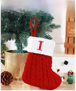 Détail d'une chaussette de Noël en tricot rouge avec revers blanc et broderie lettre I