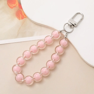 Pink bead-in-bead phone strap with silver spring clasp on soft beige background