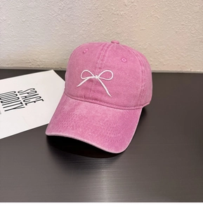 Détail de la casquette vintage rose avec broderie nœud blanc et texture denim délavé