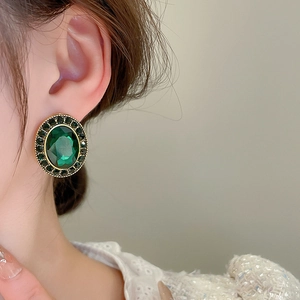 Gros plan d'une boucle d'oreille ovale émeraude vintage portée par un mannequin pro