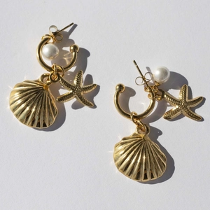 Detailed view of gold earrings featuring shell and starfish charms with pearl accents