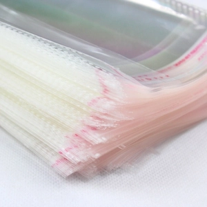 Stack of clear OPP plastic self-sealing bags with red adhesive strips for sock packaging