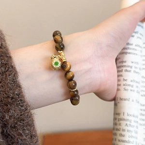 Detailed close-up of tiger eye bead bracelet with hollow golden gourd pendant and green stone