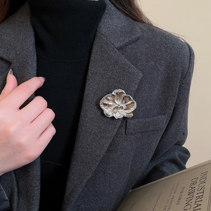 Detailed view of silver orchid flower brooch pinned on a dark grey wool blazer lapel