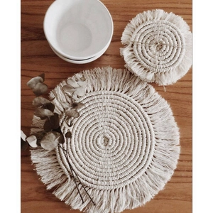 Close-up detail of handcrafted cotton woven coasters with fringe on a wooden table surface