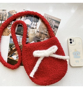 Detail of red teddy fleece bucket bag with white plush bow and soft fuzzy texture