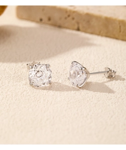 Close-up of silver S925 stud earrings with rose cut round cubic zirconia on beige stone