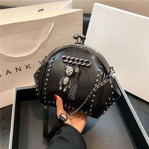 Black studded shell crossbody bag with bear pendant and tassel chain on white background