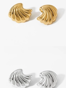 Macro detail of gold and silver shell earrings with spiral textured polished finish