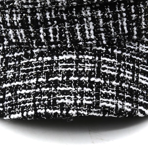 Detailed close-up of black and white tweed fabric with shimmering silver metallic threads
