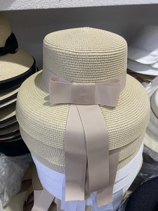 Detail of stacked straw sun hats with wide brims and elegant bow ribbon decorations
