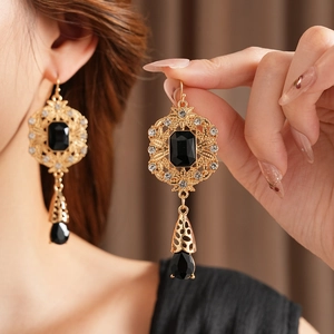 Detailed view of vintage gold hollow-carved earrings with black teardrop stones