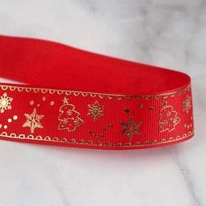Macro shot of red grosgrain Christmas ribbon with gold snowflake and tree foil patterns