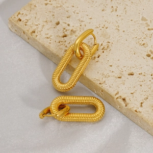Macro shot of 18K gold plated oval earrings with textured finish on silk background