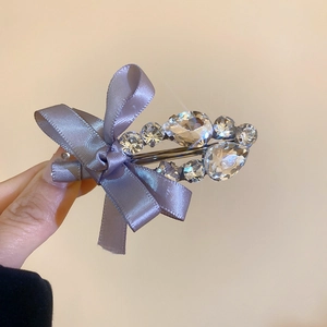 Détail d'une pince à cheveux avec nœud en satin violet et cristaux scintillants