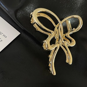 Detail of 11cm golden butterfly hair claw clip with polished finish on leather