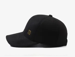 Detail view of black textured wool baseball cap with golden metal side emblem