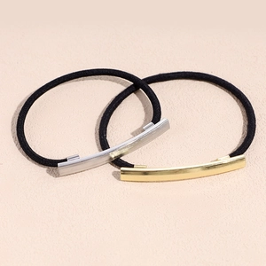 Minimalist elastic hair ties featuring gold and silver metal charms on a pink surface