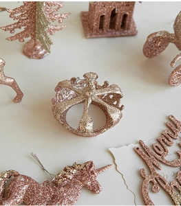 Detailed view of rose gold glitter Christmas ornaments including reindeer and tree shapes
