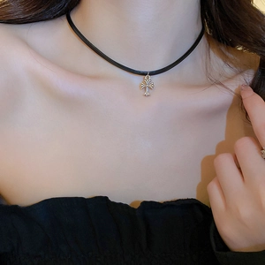 Close-up of a black faux leather choker with a silver cross pendant worn by a model