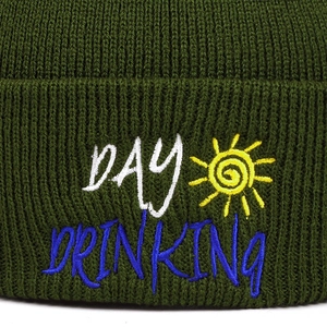 Olive green knit beanie featuring a white Day Drinking embroidery and sun motif icon