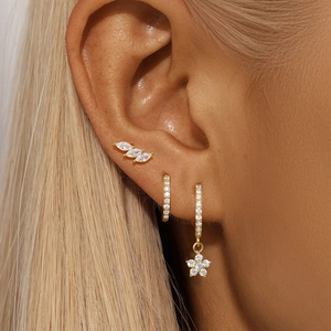 Macro shot of gold-plated silver earring set featuring flower and leaf-shaped zircons