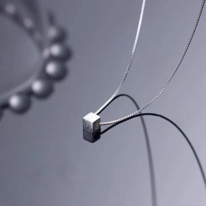 Minimalist S925 sterling silver cube necklace on reflective dark background