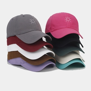 Detailed stack of cotton baseball caps in ten colors with sun embroidery on peaks