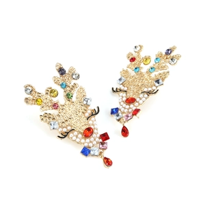 Detail of Christmas reindeer earrings with colorful rhinestones and white pearls on gold base