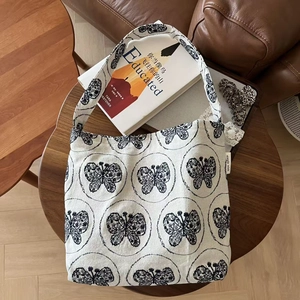 Close-up of elegant butterfly embroidery on white canvas bag with brand woven label