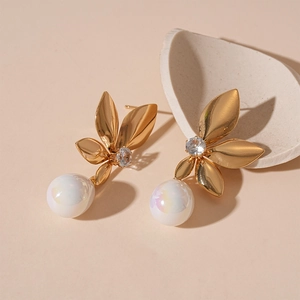 Detail of golden leaf earrings featuring a zircon center and a lustrous faux pearl drop