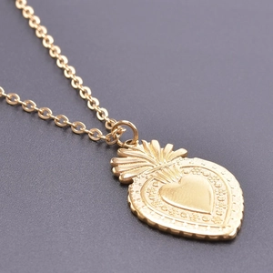 Vue macro d'un pendentif cœur doré vintage avec textures gaufrées et design rayonnant