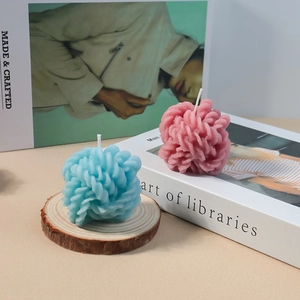 Velas de ovillo trenzado en azul y rosa sobre base de madera y libros para decoración
