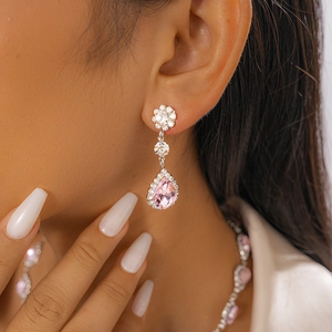 Gros plan de boucles d'oreilles rose poire avec serti halo portées sur mannequin