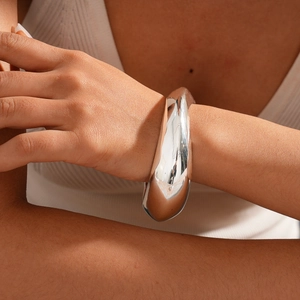 Close-up of chunky silver irregular liquid metal bangle worn by a model